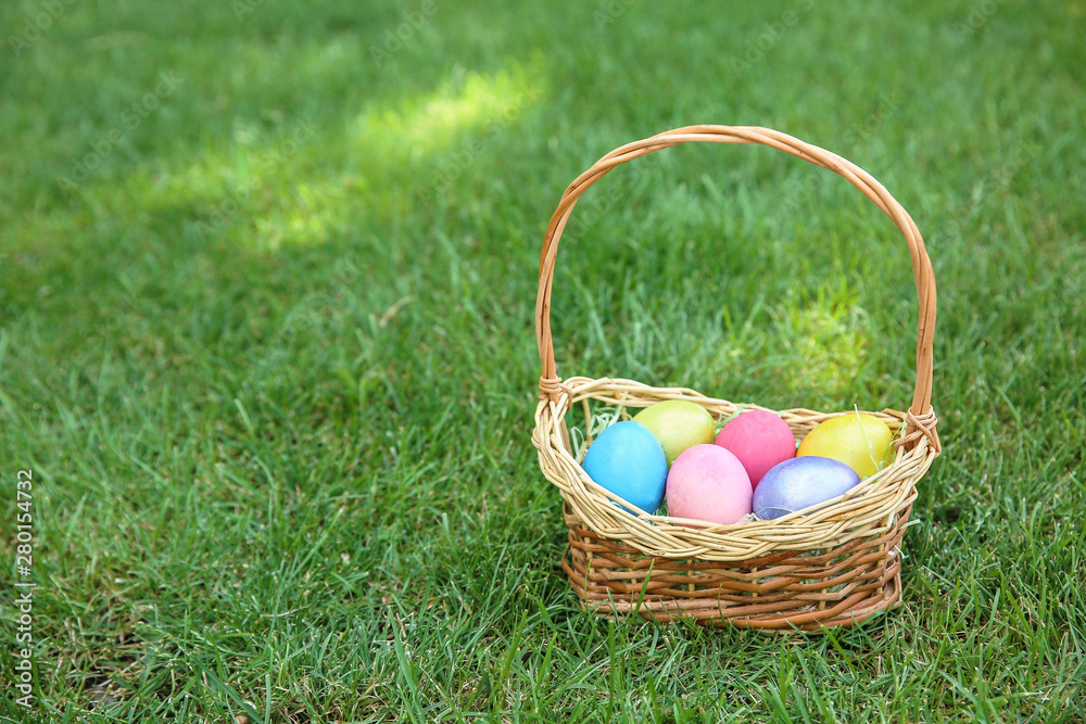 Basket with Easter eggs on grass outdoors