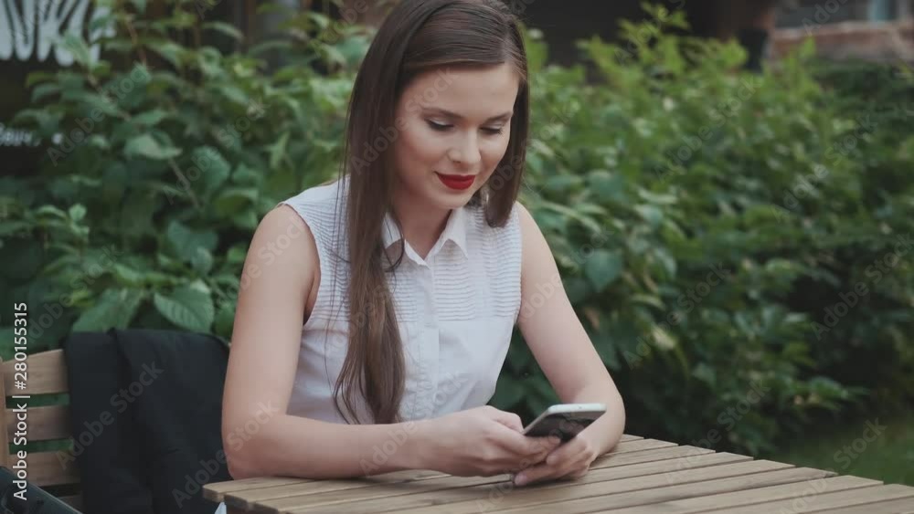 young business woman sitting in a summer cafe and chatting with a smartphone young business woman sitting in a summer cafe and chatting with a smartphone