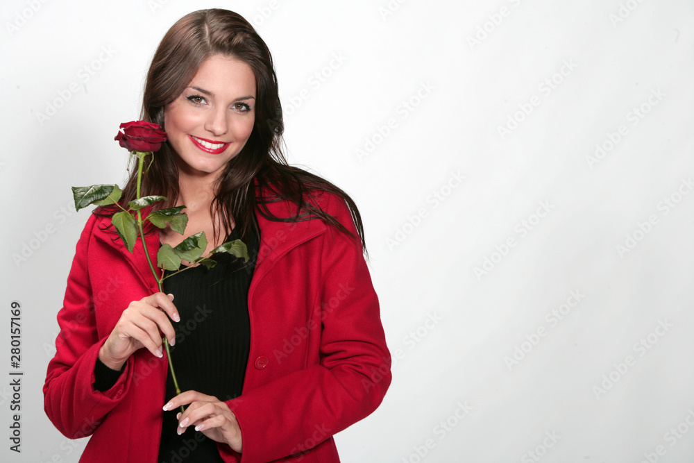 Jolie jeune femme habillée en rouge avec un rose pour la Saint Valentin