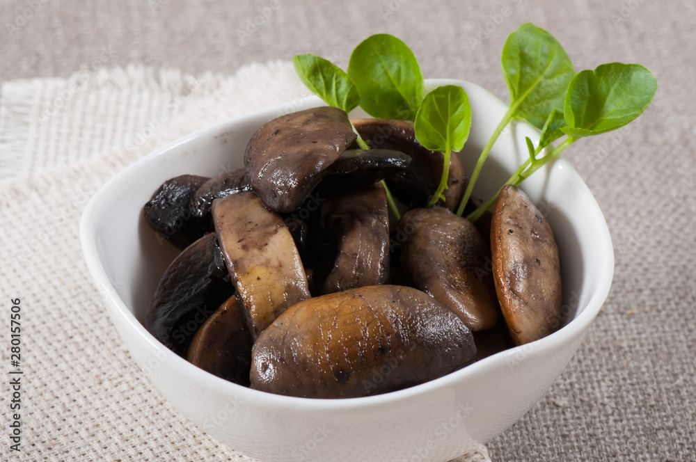 Grilled champignons in a white plate on a fabric background. Grilled champignons in a white plate on a fabric background.
