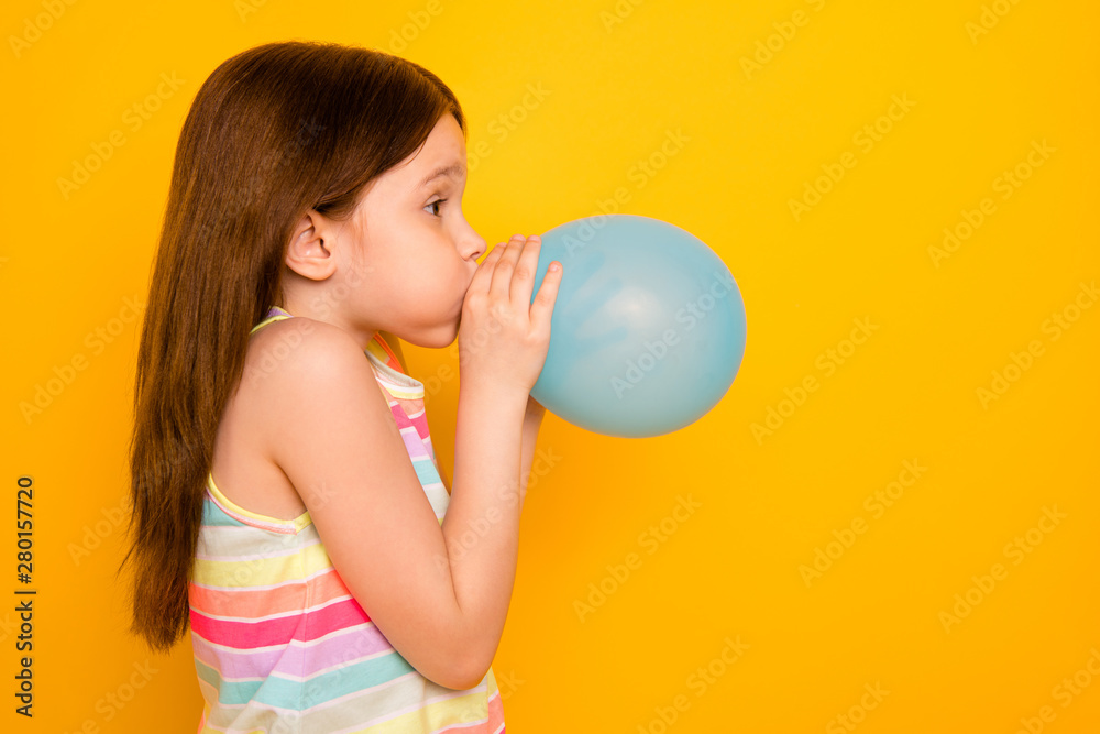 Profile side photo of charming kid inflating baloon isolated over yellow background Profile side photo of charming kid inflating baloon isolated over yellow background