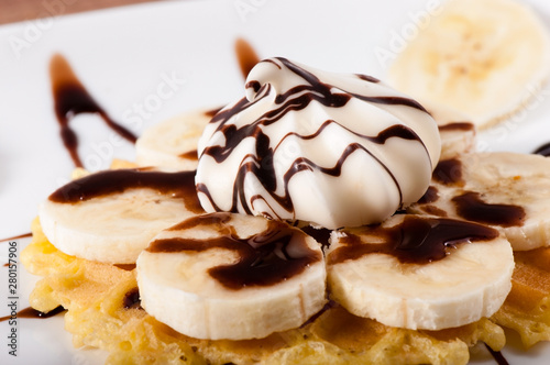 Sweet waffles with banana slices poured with chocolate sauce.