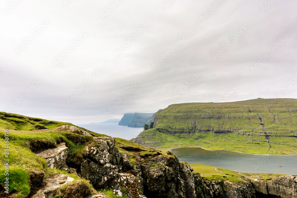 Vagar islands most picturesque hiking path along Leitisvatn lake and Bosdalafossur waterfall, Faroe Islands.