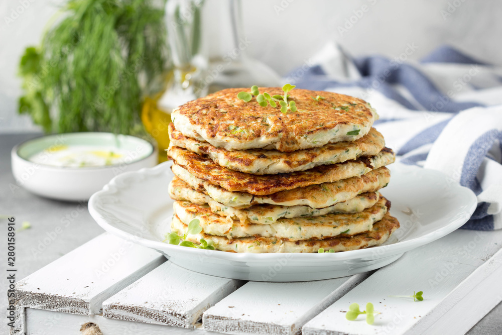 Chicken pancakes with zucchini and herbs, stack of cutlets on plate. Delicious summer food, healthy lunch with meat, vegetables, yogurt sauce Chicken pancakes with zucchini and herbs, stack of cutlets on plate. Delicious summer food, healthy lunch with meat, vegetables, yogurt sauce