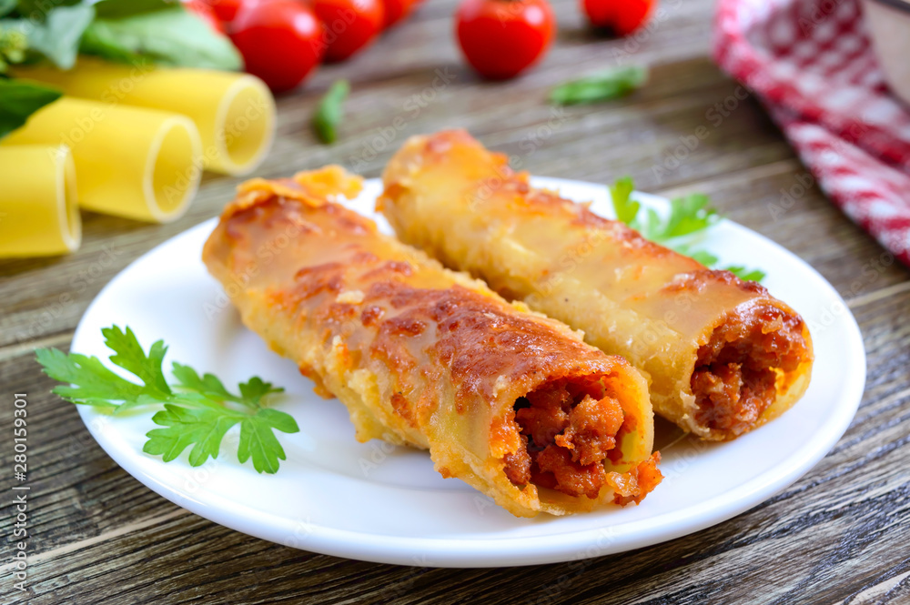 Stuffed cannelloni with bechamel sauce. Cannelloni pasta baked with meat, cream sauce, cheese on a wooden background. Stuffed cannelloni with bechamel sauce. Cannelloni pasta baked with meat, cream sauce, cheese on a wooden background.