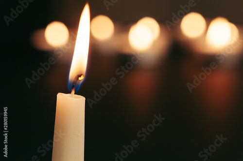 A single burning candle isolated with black background