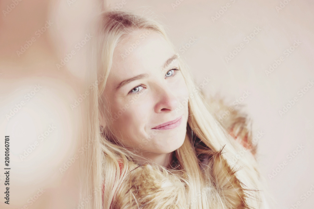 close-up portrait of a smiling blonde girl in a warm coat, cream wall background close-up portrait of a smiling blonde girl in a warm coat, cream wall background