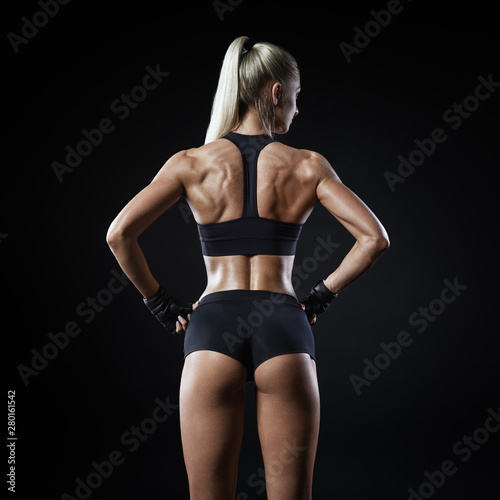 Young sports woman in sportswear stands back