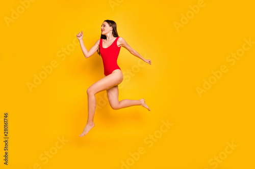 Full body profile photo of funny lady jumping high seaside sportive competitions champion speed jogging wear red swim suit isolated yellow background