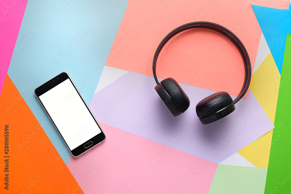 Wireless headphones and smartphone with white screen for layout on color background Wireless headphones and smartphone with white screen for layout on color background