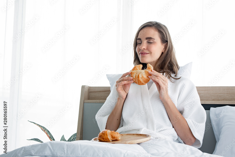 Young woman caucasian in pajama eat bread after I woke up the morning. Young woman caucasian in pajama eat bread after I woke up the morning.