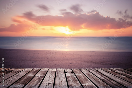 Colorful beautiful cloudy sunset over ocean with wooden path