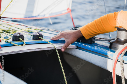Man's hand with boat rope. Yachtsman moors his motor boat at jetty. Close up hands and bow of the boat.