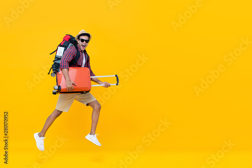 Handsome Indian tourist man with backpack holding baggage and jumping