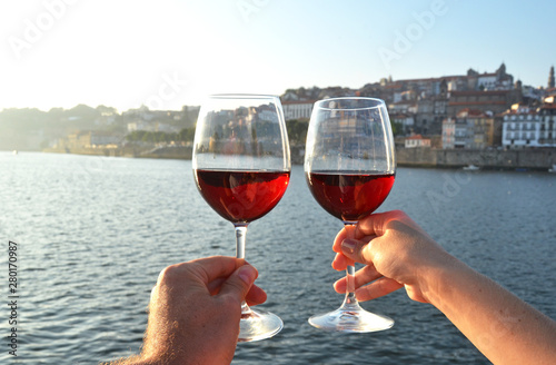 Wine glasses in the hands against Douro river in Porto, Portugal
