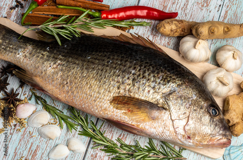 Fresh Golden Snapper on wooden table, Surrounded by spices and raw ingredients