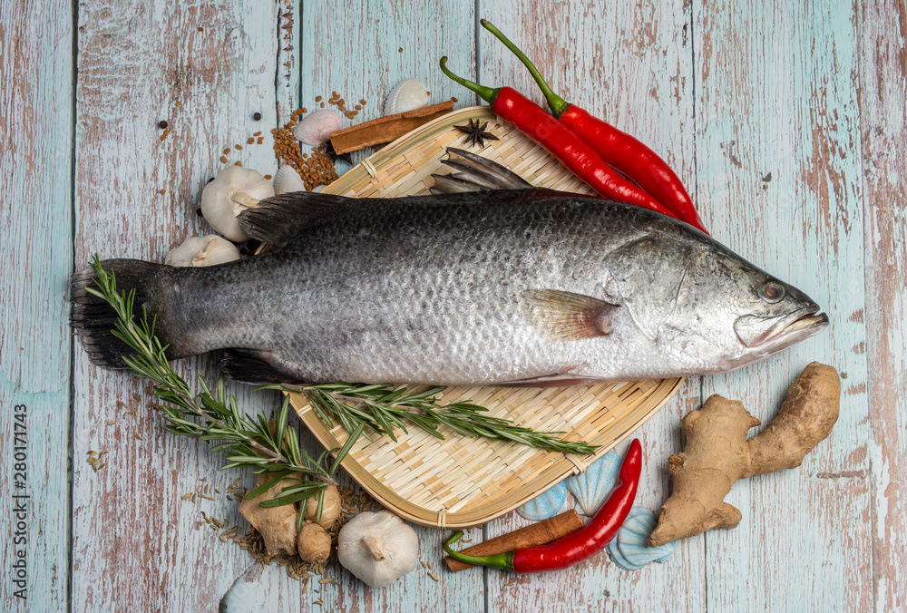 Fresh Sea Bass on rattan plate and wooden background Fresh Sea Bass on rattan plate and wooden background