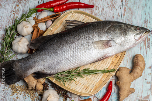 Fresh Sea Bass on rattan plate and wooden background