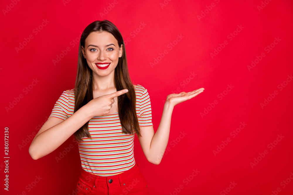Pretty lady indicating arm on open palm with new product wear casual outfit isolated burgundy background Pretty lady indicating arm on open palm with new product wear casual outfit isolated burgundy background