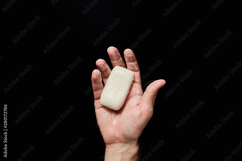 top view of man holding white soap isolated on black