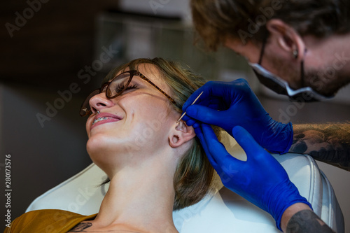 Man showing a process of piercing with steril medical equipment and latex gloves. Marking the piercing spot. Body Piercing Procedure