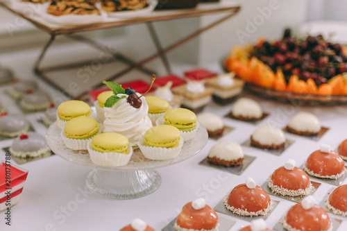 Beautifully decorated catering banquet table with burgers, profiteroles, salads and cold snacks. Variety of tasty delicious snacks on the table