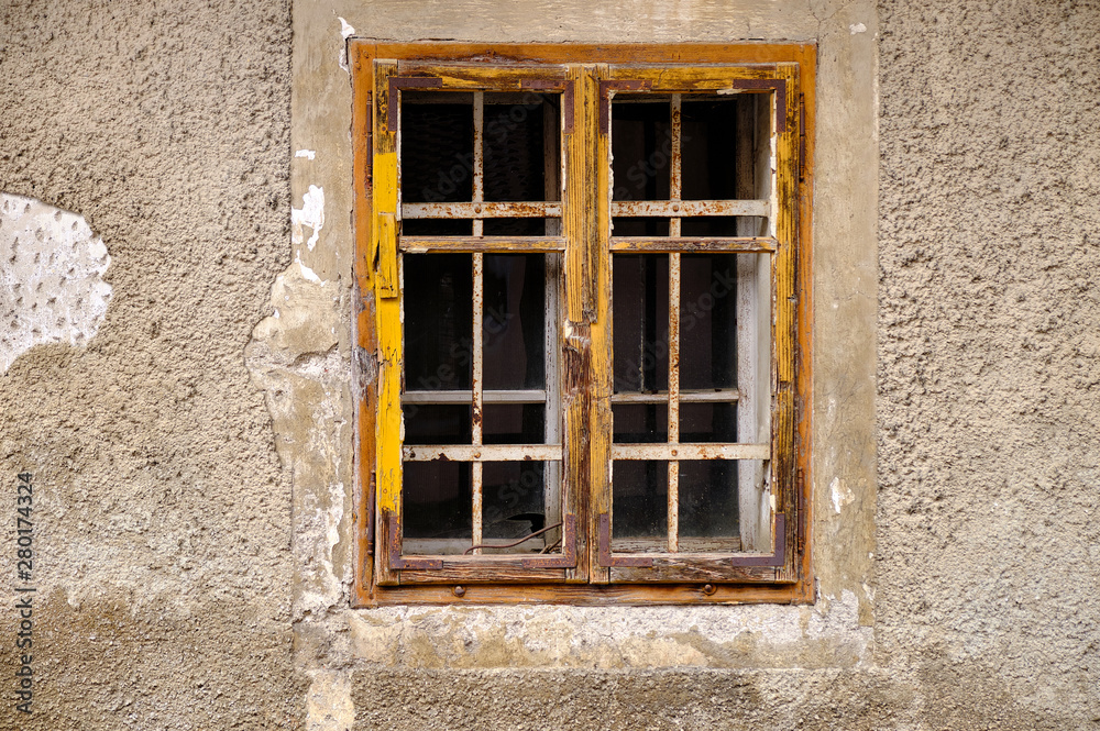 Minimalist capture of a single rural window on a grey textured wall with peeling concrete. Simple window with yellow frame and mullions Minimalist capture of a single rural window on a grey textured wall with peeling concrete. Simple window with yellow frame and mullions