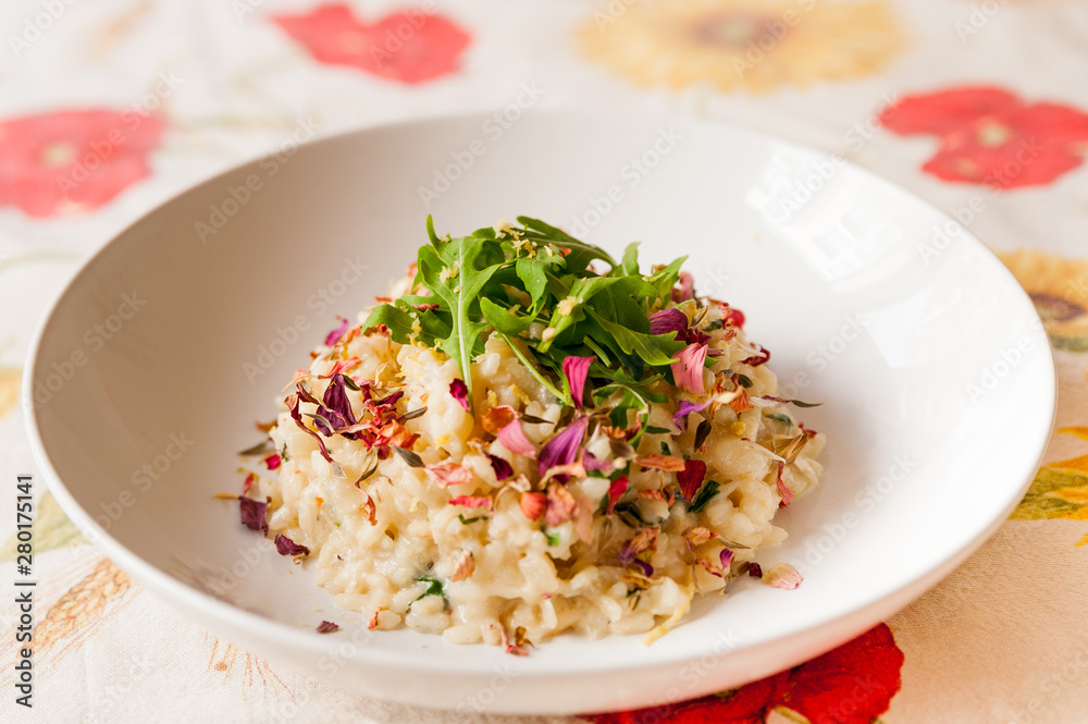 close up of delicious italian homemade risotto on table cloth with arugula salad lemon and edible flowers and soft natural light close up of delicious italian homemade risotto on table cloth with arugula salad lemon and edible flowers and soft natural light