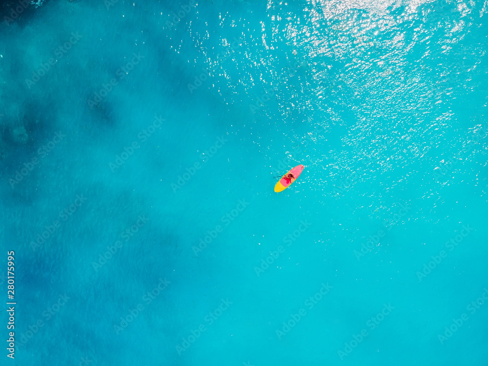 Aerial view of woman on stand up paddle board in blue ocean. Aerial view of woman on stand up paddle board in blue ocean.