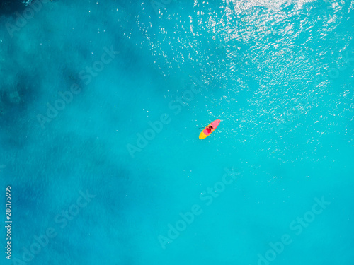 Aerial view of woman on stand up paddle board in blue ocean. © artifirsov