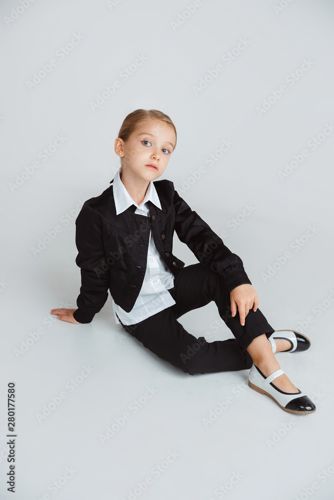 Girl preparing for school after a long summer break. Back to school. Little female caucasian model posing in school's uniform on white studio background. Childhood, education, holidays concept. Girl preparing for school after a long summer break. Back to school. Little female caucasian model posing in school's uniform on white studio background. Childhood, education, holidays concept.