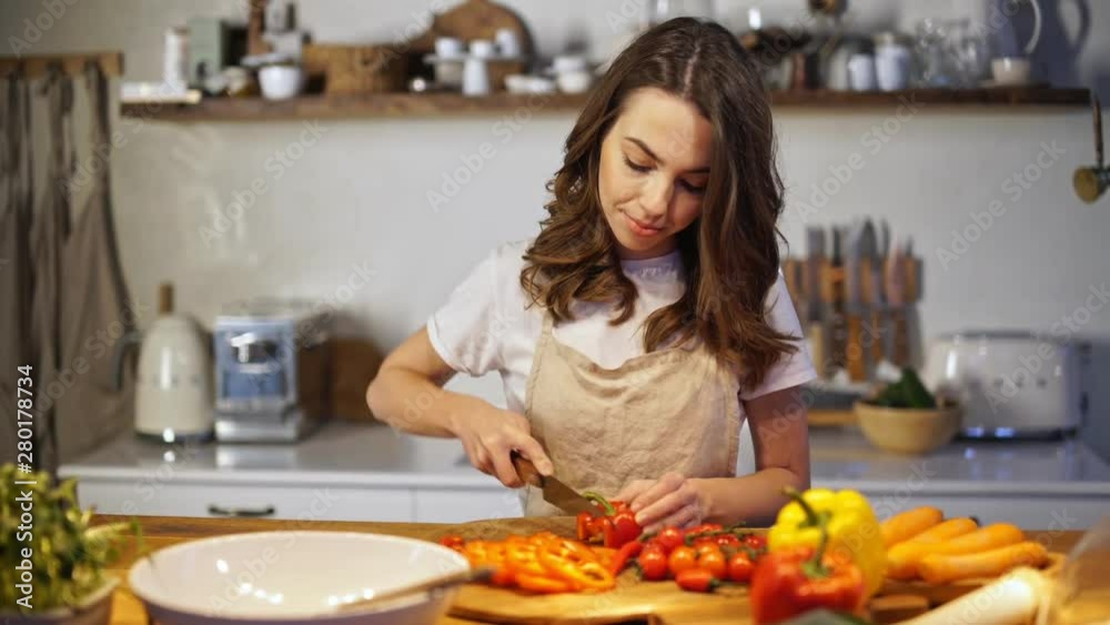 Young woman in apron getting tired while cooking in the kitchen