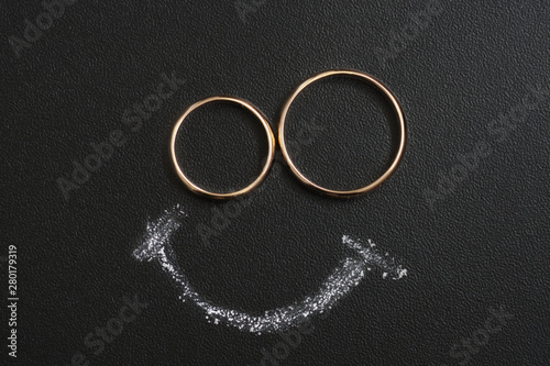 Wedding rings and smile drawing with calk on calkboard.
