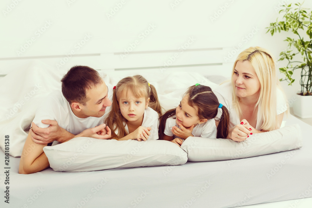 Children and parents rest in the morning in bed. They indulge, hug. Twins. daughters. Children and parents rest in the morning in bed. They indulge, hug. Twins. daughters.