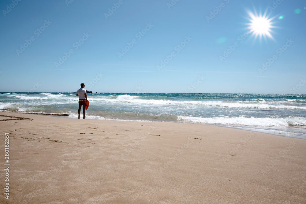 A lifeguard boy on the beach in a summer sunny day