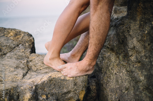 close up legs of kissing couple near the sea on the rocks