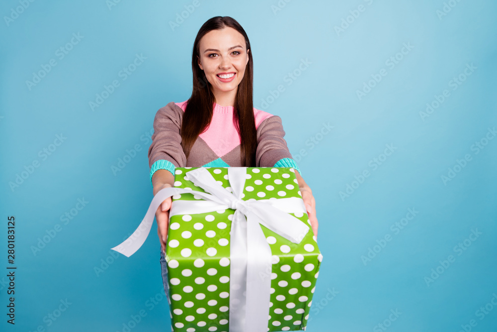 Portrait of white lovely content serene sweet girl holding large wrapped in dotted paper box givving you isolated vivid background Portrait of white lovely content serene sweet girl holding large wrapped in dotted paper box givving you isolated vivid background