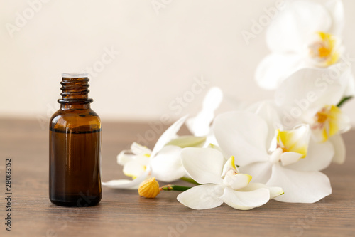 Spa concept with white orchids and bottle of essential oil, space for text. Massage oil. Orchid flower with natural oil in the Spa salon. 