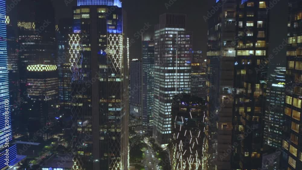 JAKARTA, Indonesia - July 15, 2019: Aerial scenery of dense modern office buildings with beautiful night lights in business center. Shot in 4k resolution from a drone flying forwards JAKARTA, Indonesia - July 15, 2019: Aerial scenery of dense modern office buildings with beautiful night lights in business center. Shot in 4k resolution from a drone flying forwards
