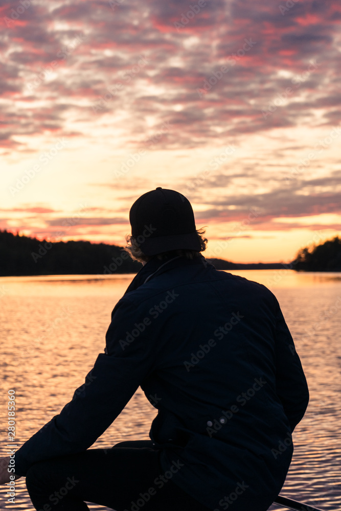Person sitting in the front of the boat watching the golden sunset
