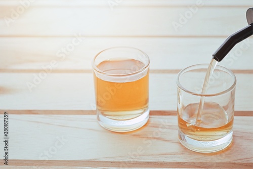 closeup pour a small glass of liquor on wood table.