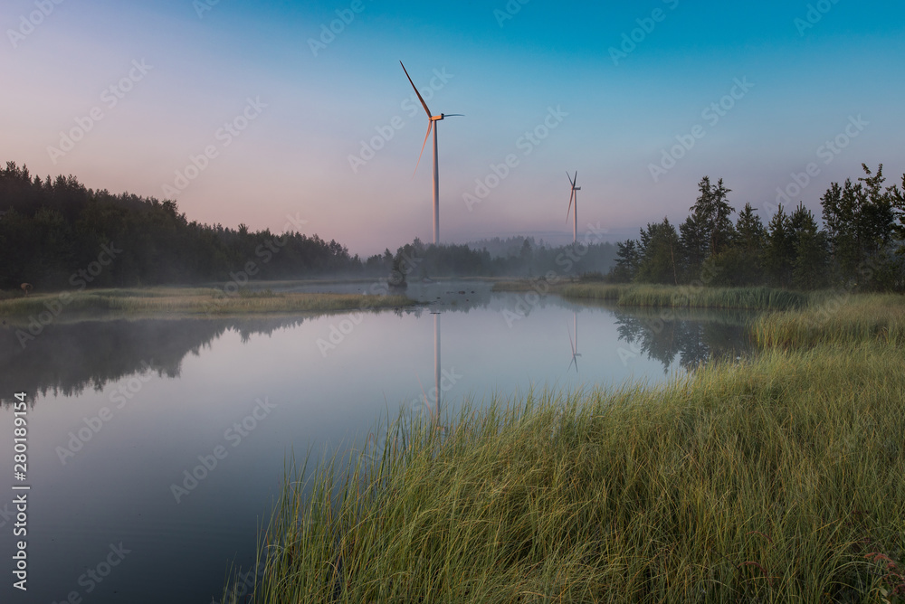 Windmill with first sunlight above misty pond