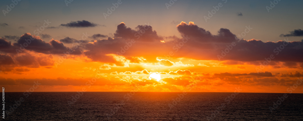 Natural marine landscape with amazing sunset over the ocean in Fuerteventura Canary Island Spain. Summer exotic vacation postcard from tropical islands. Orange sunrise over the water behind the clouds