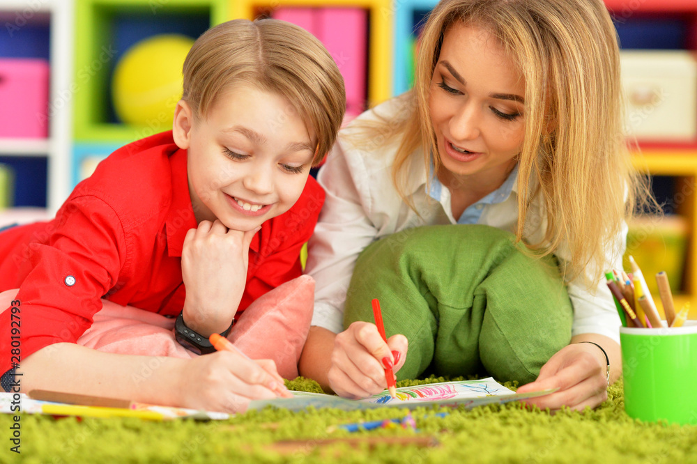 Close up view of smiling mother and son drawing with pencils