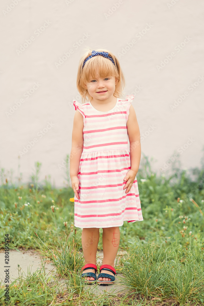 Pretty little girl standing on pink background and holding ponytails on her head. Pretty little girl standing on pink background and holding ponytails on her head.