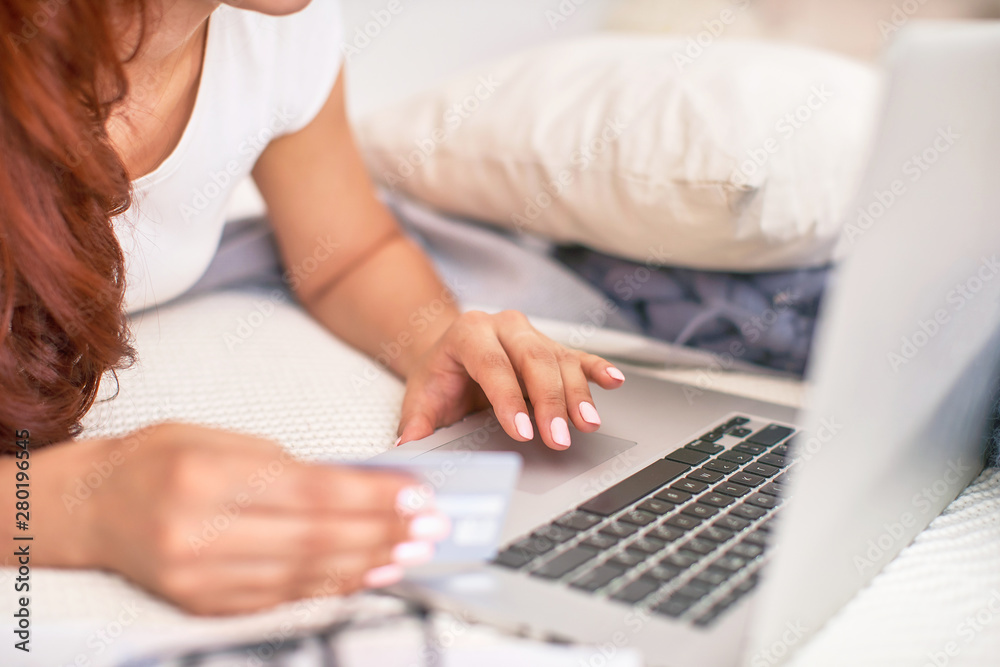 the student is happy to communicate with friends via the Internet. home schooling, work and study, new knowledge.happy teen on bed with computer. girl student lying on the bed smiling. the student is happy to communicate with friends via the Internet. home schooling, work and study, new knowledge.happy teen on bed with computer. girl student lying on the bed smiling.