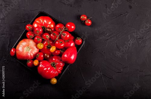 Tomatoes on black background top view copy space.