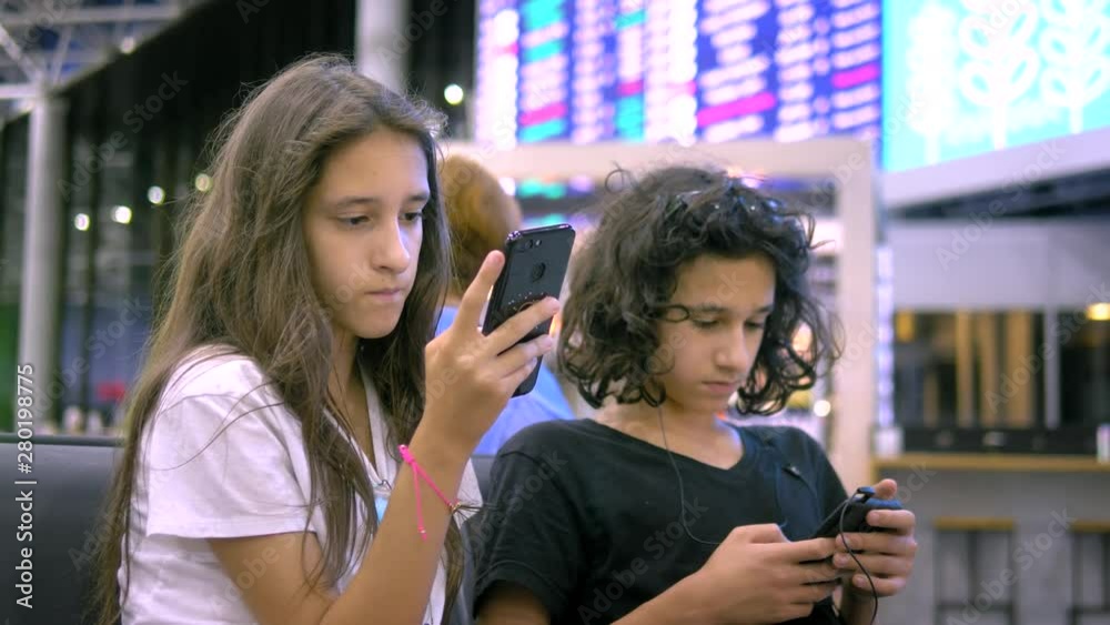 Children in the airport waiting area use a smartphone. travel concept Children in the airport waiting area use a smartphone. travel concept