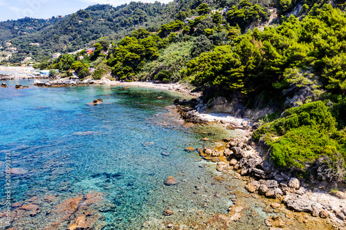 Aerial view of beautiful green and rocky island in the blue ocean.