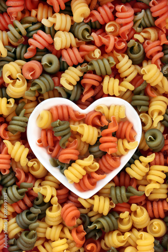 Trottole tricolour pasta in a heart shaped dish and loose forming an abstract background.
